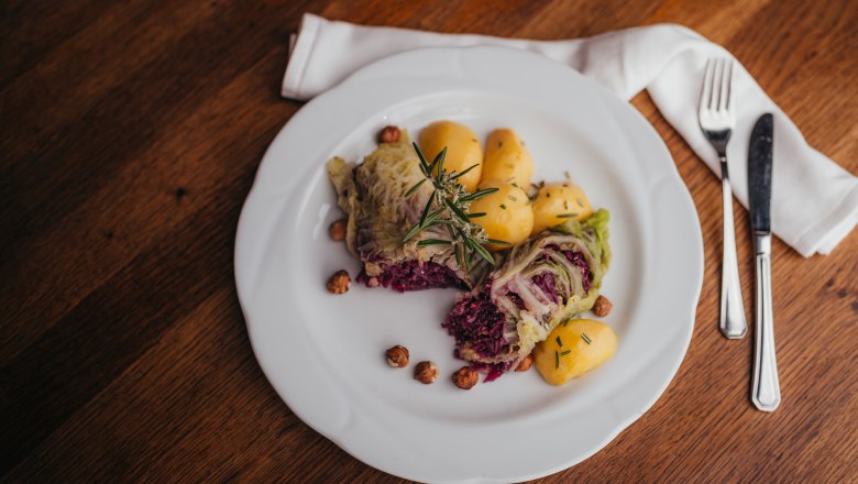 Cabbage leaves with nut filling, © Niederösterreich Werbung/Daniela Führer A plate of stuffed cabbage leaves, potatoes and nuts, garnished with rosemary.