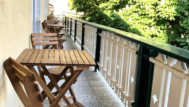 TDR-GasthofKirchenwirth-Balkon, © Josef Burger Holzbalkon mit Tisch und Stühlen, daneben grüne Bäume.