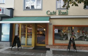 Cafe Exel, © Roman Zöchlinger Außenansicht des Café Exel mit grüner Markise und Schaufensterdekoration.
