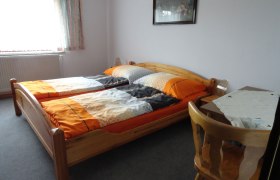 Zimmeransicht, © Schreiblehner Ein einfach eingerichtetes Schlafzimmer mit zwei Einzelbetten, einem Tisch und einem Stuhl.