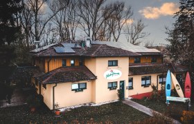 Naturefriends boathouse, © Niederösterreich Werbung/ David Schreiber A building with solar panels on the roof and a sign saying 'Friends of Nature'. There are three colorful canoes in front of the building.
