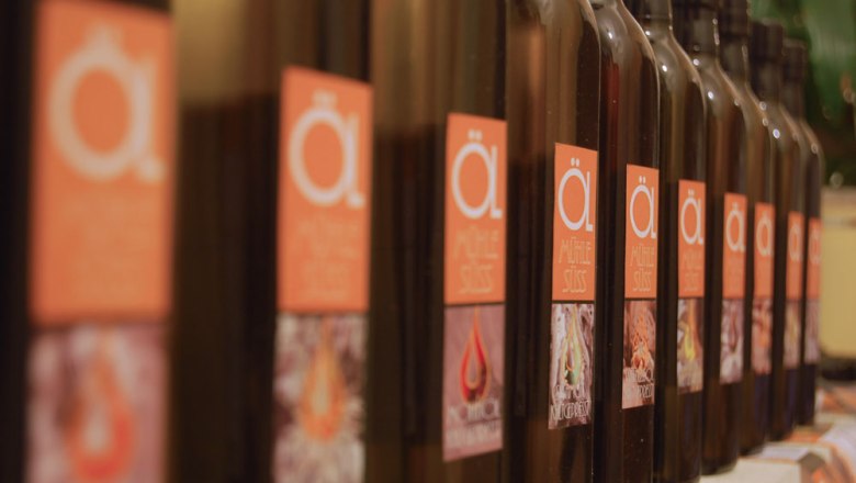 Ölmühle Süss, © Ing. Johann Süss Reihe von Ölmühle Süss Flaschen mit orangefarbenen Etiketten.