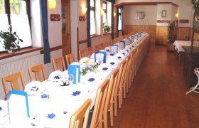 Saal Gasthaus Mahrer, © Archiv Betrieb Ein langer, festlich gedeckter Tisch in einem Saal mit Holzboden und Holzdecke.