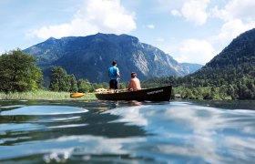 Fisherman at the lake, © Weinfranz.at Two people in a boat on a lake, surrounded by mountains and trees.