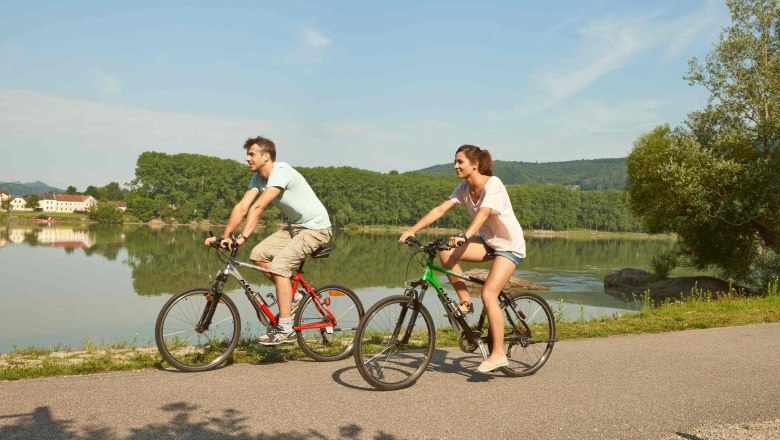 Cyclists in the Nibelungengau, © Klaus Engelmayer Two cyclists ride on a path along a river in the Nibelungengau.