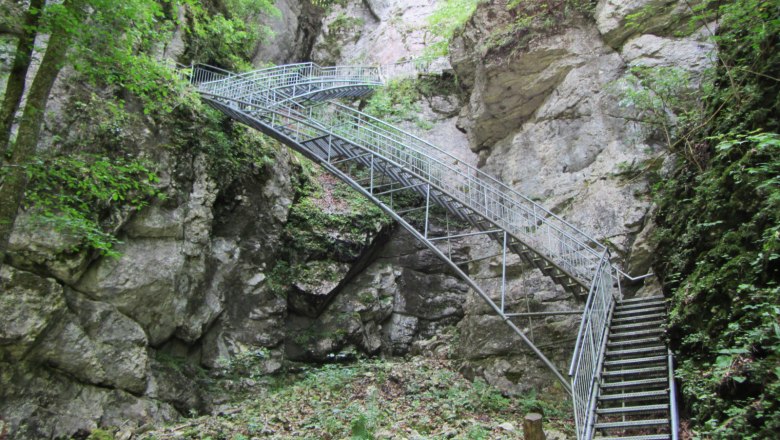 Erlebnissteiganlage hinauf zur Ötscher Tropfsteinhöhle, © Mostviertel Tourismus, Karas Metalltreppe in einer felsigen Schlucht mit grüner Vegetation.