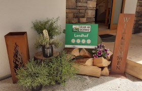 Eingangsbereich, © Maria Harrauer Eingangsbereich mit Holzscheiten und einem Willkommensschild.