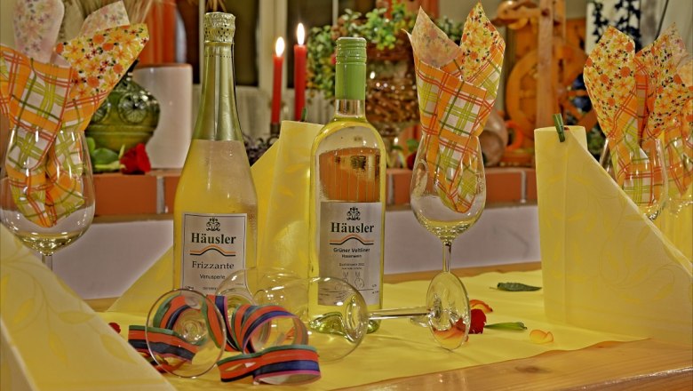 Weinbau Häusler, © zur Verfügung gestellt: Weinbau Häusler Festlich gedeckter Tisch mit Weinflaschen und Gläsern.