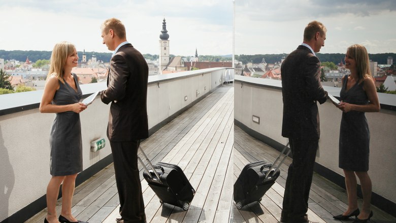 Provincial capital St. Pölten, © schwarz-koenig.at Two people are standing on a roof terrace in St. Pölten with a view of the city and talking.