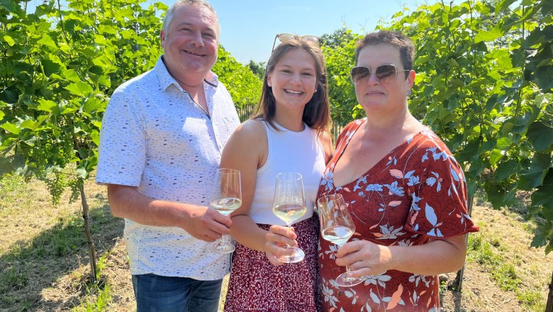 familie-haimel_1, © Weingut Haimel Familie Heimel mit Weingläsern in der Hand. Die Familie steht zwischen Weinreben.