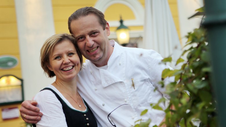 Gruber-Rosenberger family, © Weinfranz A smiling couple in traditional dress in front of a yellow building.
