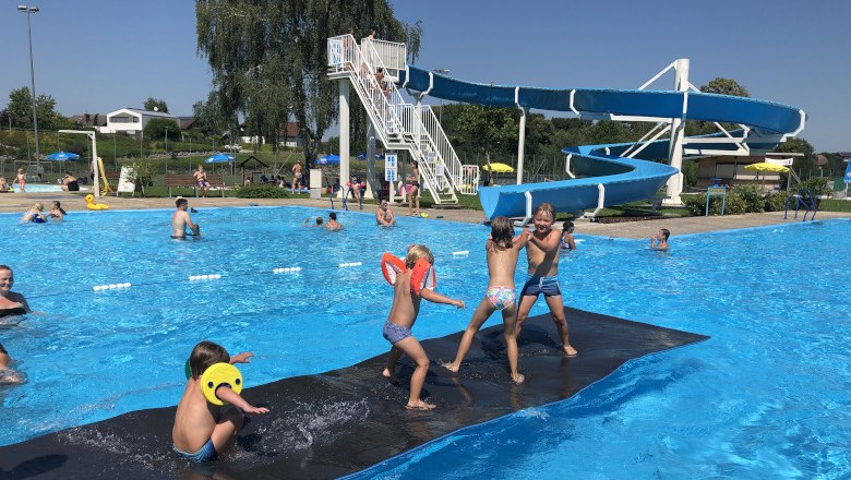 Neuhofen an der Ybbs outdoor pool, © Gemeinde Neuhofen Children play on a floating mat in front of a water slide at the Neuhofen an der Ybbs outdoor pool.