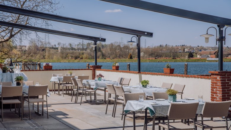Terrasse mit Blick auf den Stausee, © Niederösterreich Werbung/thecreatingclick.com Terrasse mit Tischen und Stühlen, Blick auf einen Stausee und umliegende Landschaft.