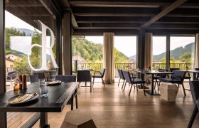 Refugium Lunz, © Niederösterreich Werbung / Maximilian Pawlikowsky Innenansicht eines modernen Restaurants mit großen Fenstern und Blick auf bewaldete Hügel.