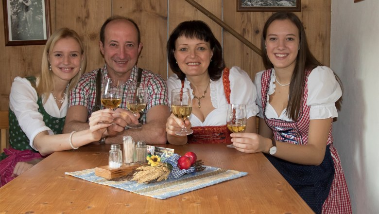 Lampersberger family, © Barbara Wagner A family in traditional dress clinks glasses of wine at a wooden table.