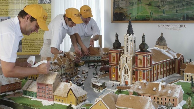 Pirker's gingerbread, © zVg Familie Pirker Three people decorate a gingerbread model of Mariazell around 1800.