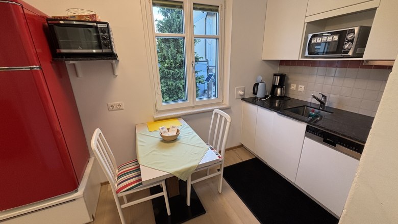 TDR-Haus Morgensonne Küche, © Fam Pauker Kleine Küche mit rotem Kühlschrank, Tisch, Stühlen und Fenster.