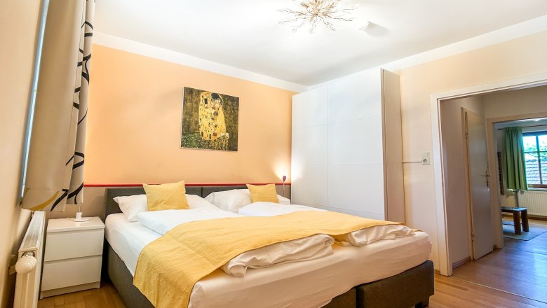 Haus Morgensonne Schlafzimmer II, © Fam. Pauker Schlafzimmer mit Doppelbett, gelber Bettwäsche und Kunstwerk an der Wand.