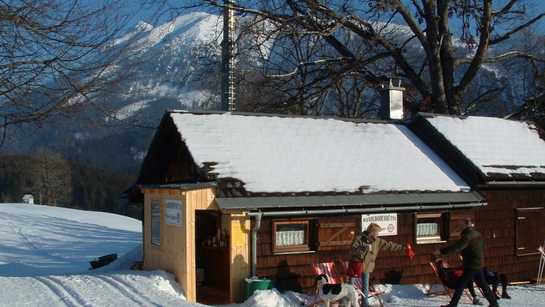 Mandlbodenhütte, © Familie Egger Winterliche Berghütte mit Menschen und Hund im Schnee.