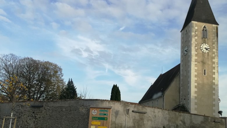 Kirche Hafnerbach, © Roman Zöchlinger Kirche mit Turm und Uhr in Hafnerbach, umgeben von einer Mauer.
