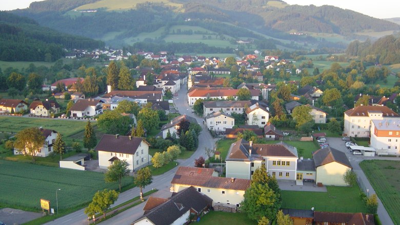 Wang, © Gemeinde Wang Luftaufnahme eines Dorfes mit Häusern, Straßen und umliegenden Hügeln im Hintergrund.
