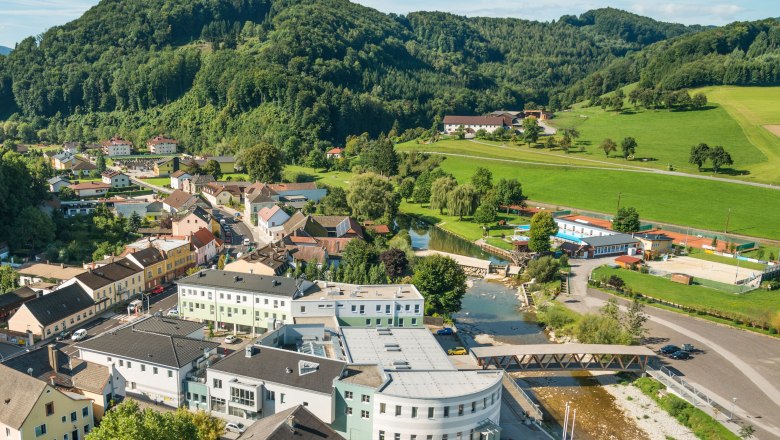 Rabenstein Zentrum, © Markus Haslinger - www.extremfotos.com Luftaufnahme eines kleinen Dorfes mit Fluss, Brücke und umliegenden Hügeln.