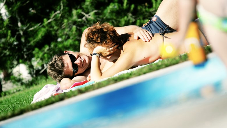 Lounging on the sunbathing lawn, © weinfranz.at A couple is relaxing on a lawn next to a pool.