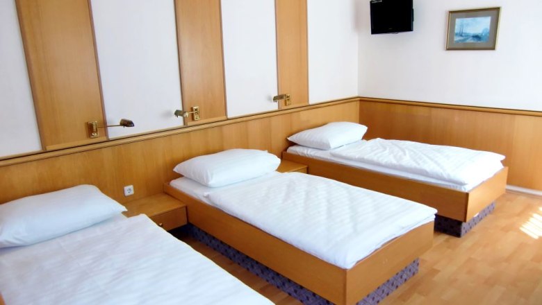 Triple room, © Weinberger Triple room with three single beds, wooden walls, TV and picture on the wall.