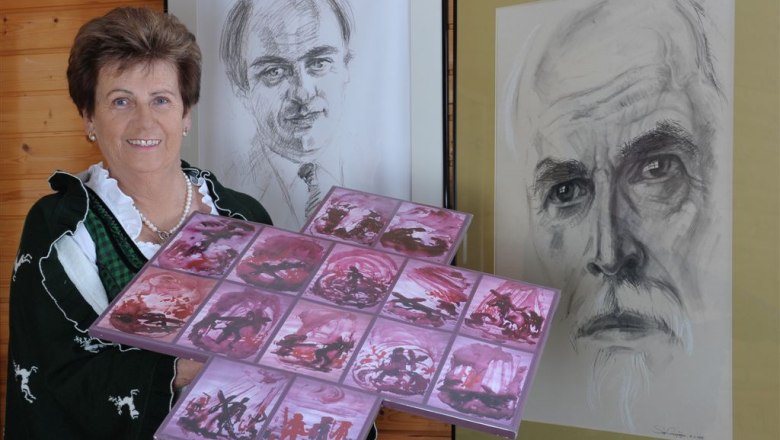 Way of the Cross, © gamsburg Woman in traditional costume holding artwork in front of two portraits.