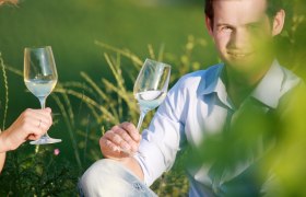 Traisental, © weinfranz.at Zwei Personen stoßen mit Weingläsern im Freien an.