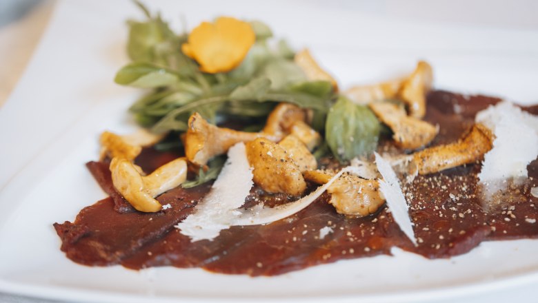 There is also: Fallow deer carpaccio & pickled chanterelles, © Niederösterreich Werbung/David Schreiber Fallow deer carpaccio with pickled chanterelles and rocket on a white plate.