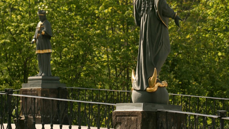 Töpperbrücke Lunz am See, © Lunz am See Zwei Statuen auf einer Brücke mit Geländer, umgeben von grünen Bäumen.