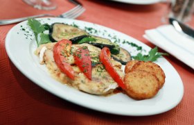 Schmankerln, © weinfranz.at Ein Teller mit gebratenem Gemüse, Tomaten und Rösti auf einem roten Tisch.