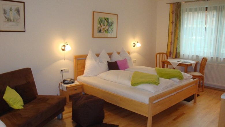 Room Apple Blossom, © Gästehaus Daurer Comfortable hotel room with double bed, sofa and dining table.