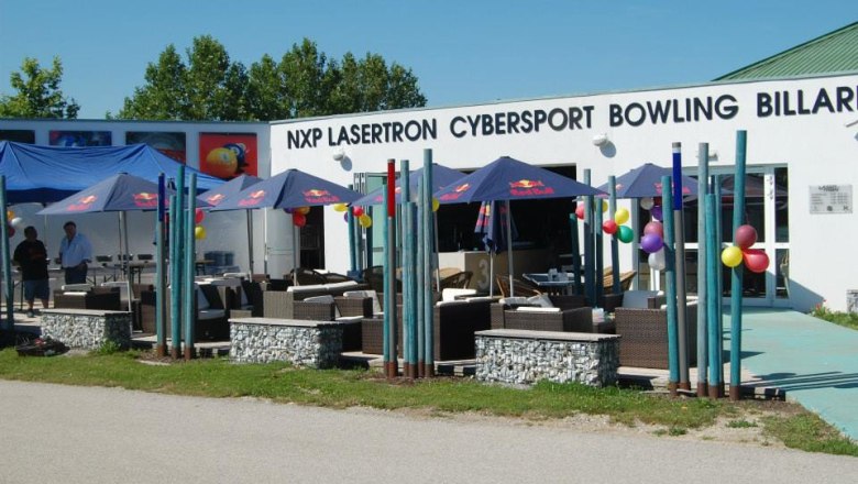 NXP Lasertron, © NXP Lasertron Außenansicht eines Freizeitzentrums mit Schirmen und Sitzgelegenheiten.