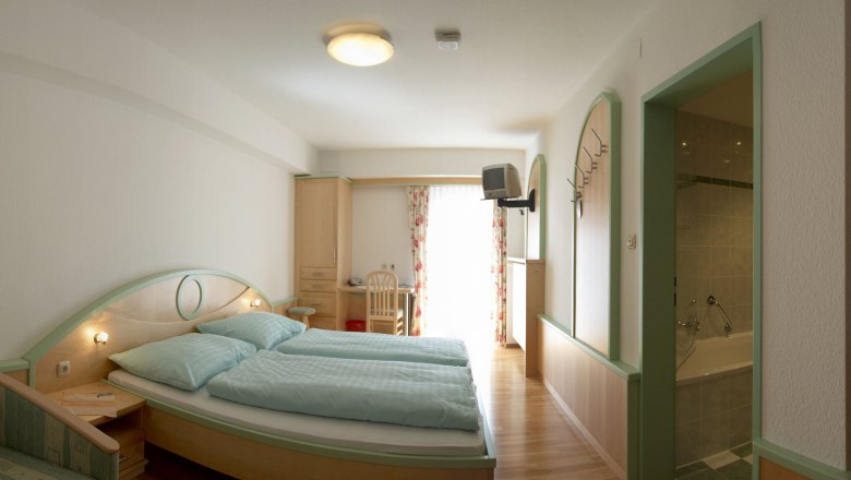 Standard room, © zVg Kirchenwirt A hotel room with double bed, desk, TV and bathroom.