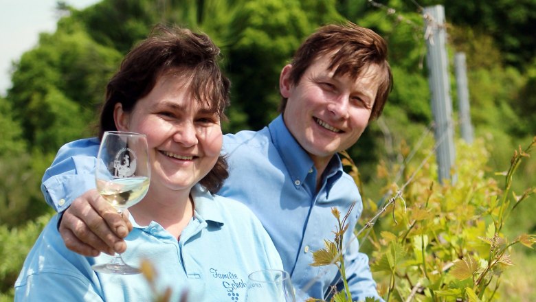 Familie Schabasser, © Schabasser Zwei Personen in einem Weinberg mit Weingläsern.