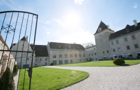 Walpersdorf Castle Entrance, © Schwarz-König.at Entrance to Walpersdorf Castle with open gate, lawn and historic building in the background.