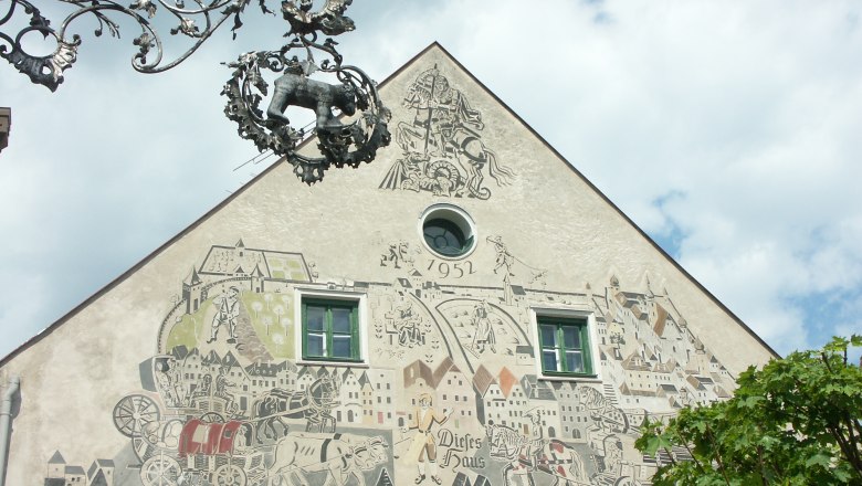 Sgraffitohaus, © Dominik Stixenberger Fassade eines Hauses mit Sgraffito-Kunstwerk und dekorativem Metallschild.