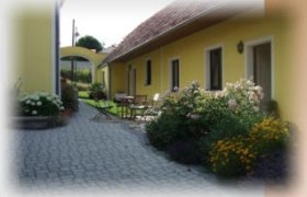 Hausansicht, © Der Teichhof Gelbes Haus mit Garten und gepflastertem Weg.