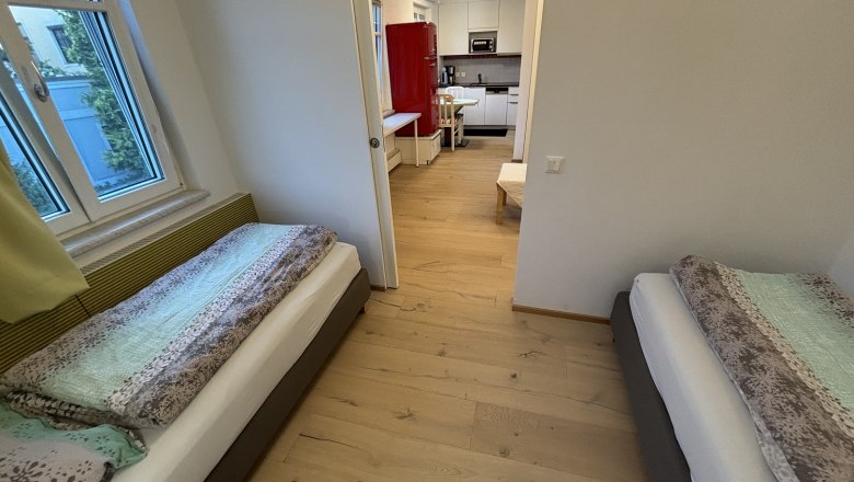 TDR-Haus Morgensonne Schlafzimmer, © Fam Pauker Schlafzimmer mit zwei Einzelbetten und Blick in die Küche.
