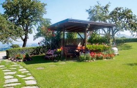 bauernhof Oberschönbichl, © Oberschönbichl Ein Pavillon auf einem grünen Rasen mit bunten Blumen und Bäumen im Hintergrund.