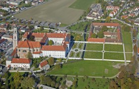 Flugaufnahme, © Hans Kopitz Luftaufnahme eines großen Gebäudekomplexes mit roten Dächern und Gartenanlagen.