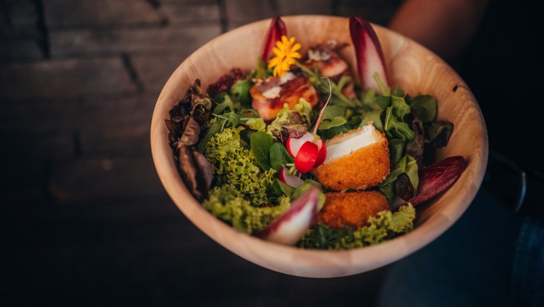 Baked Mostviertel sheep's cheese on leaf salad, © Niederösterreich Werbung/Daniela Führer Wooden bowl with lettuce, baked sheep's cheese and radishes.