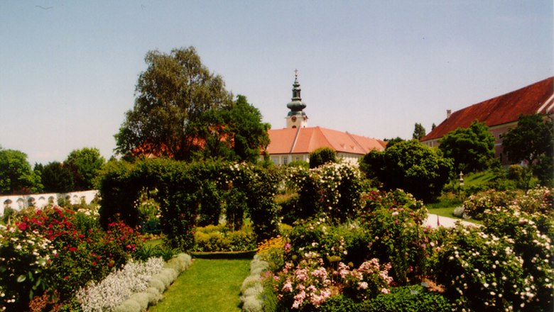 Historic courtyard garden Seitenstetten Abbey, © Gemeinde Seitenstetten Historic garden with flowers and trees, in the background a building with a tower.