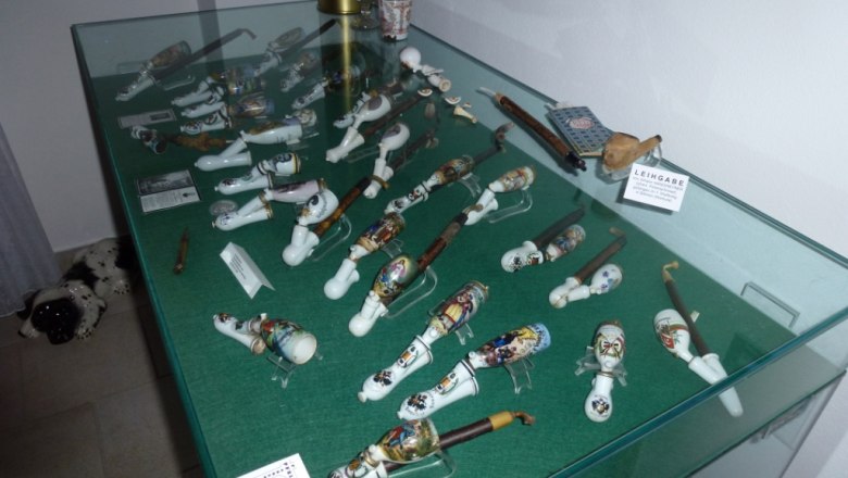 Pipe museum, © Marktgemeinde St. Aegyd/Neuwalde Display case with decorative pipes in a museum.