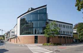 Bildungshaus St. Hippolyt, © Werner Jäger Modernes Gebäude mit Glasfassade und Ziegelmauerwerk an einer Straßenecke.