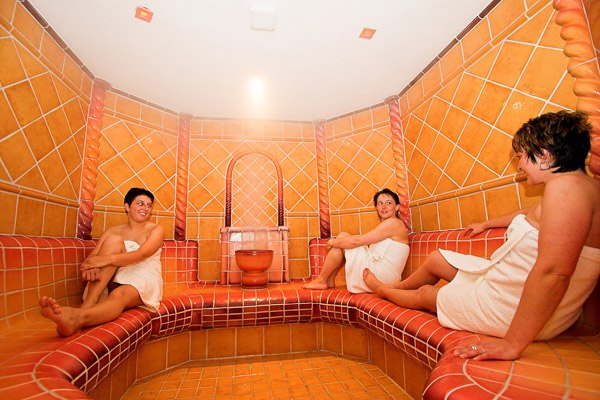 Flösser Pfand'l, © Christian Fürnholzer Drei Personen in einem gefliesten Dampfbad, eingewickelt in Handtücher.
