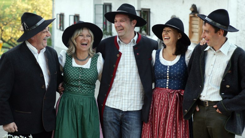 Rent A Sepp, © zVg Gruppe von fünf Personen in traditioneller bayerischer Tracht, die fröhlich lachen.
