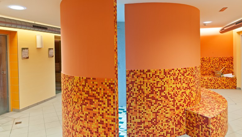 Fitness & Wellness Jufa Hochkar, © zVg Jufa Hochkar Interior view of a wellness area with orange mosaic tiles and round walls.